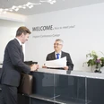Fraport Conference Center - Reception area Empfangssituation am Counter mit Gast und Mitarbeiter.Reception situation at the counter with guest and employee.