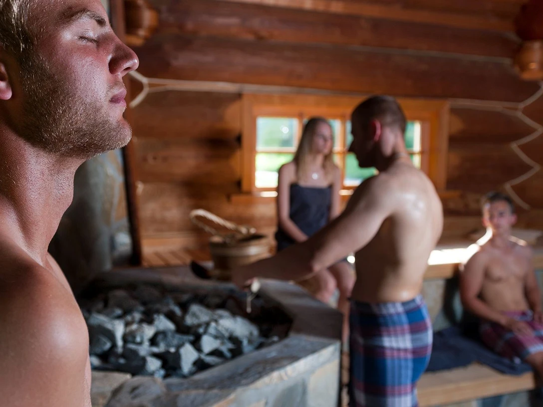 Lange Saunanacht Personen entspannen in einer Holzsauna bei einem Aufguss in ruhiger Wohlfühlatmosphäre.