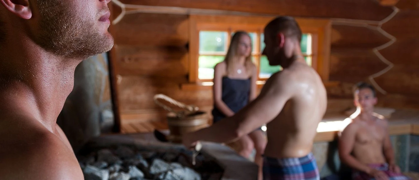Lange Saunanacht Personen entspannen in einer Holzsauna bei einem Aufguss in ruhiger Wohlfühlatmosphäre.