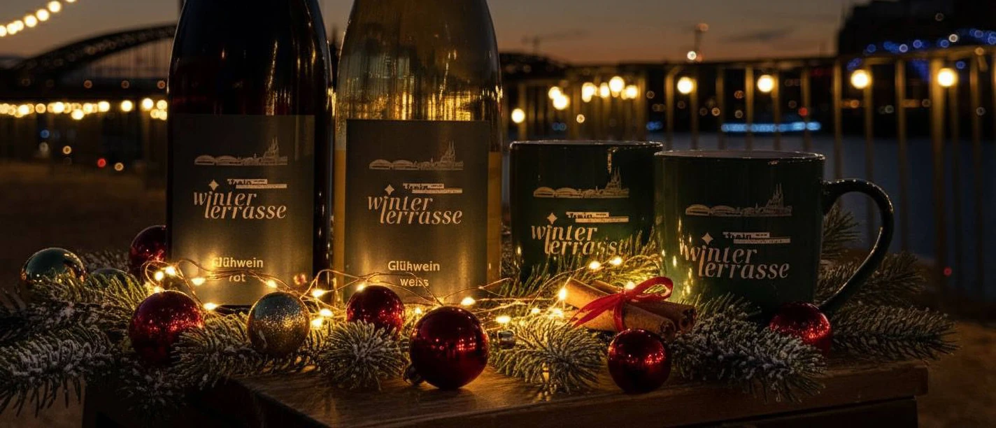 Winterterrasse Köln Zwei Glühweinflaschen und Becher vor Lichterkette bei Abendstimmung mit festlicher Deko.