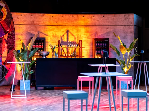 Vogel Event Partner - Bar area Barbereich mit warmer Ambientebeleuchtung und Hochtischen im Vordergrund.