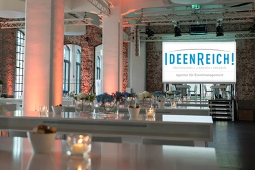 IdeenReich! GmbH - Event space Event space with brick walls, white columns and high tables.