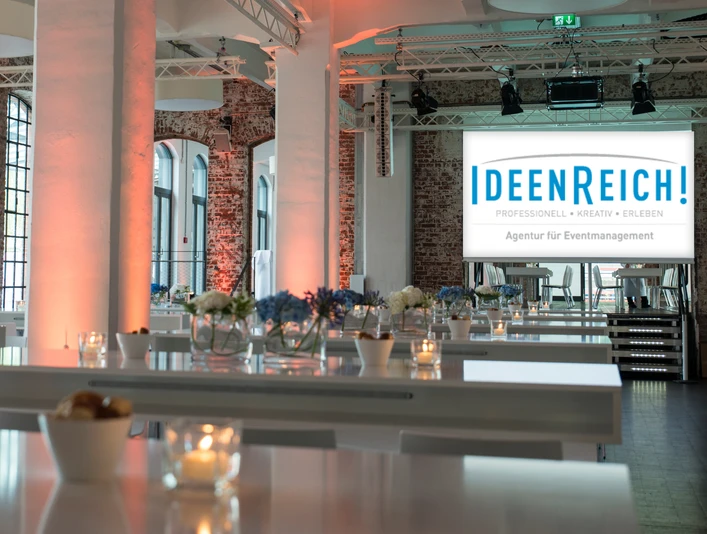 IdeenReich! GmbH - Event space Event space with brick walls, white columns and high tables.