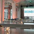 IdeenReich! GmbH - Veranstaltungsraum Veranstaltungsraum mit Backsteinwänden, weißen Säulen und Hochtischen.