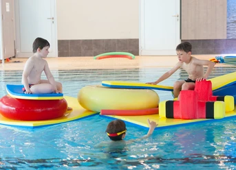 Spielenachmittag.jpg Kinder spielen fröhlich im Wasser auf bunten Schwimmkissen in der Sole-Therme Otterndorf.