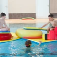 Spielenachmittag.jpg Kinder spielen fröhlich im Wasser auf bunten Schwimmkissen in der Sole-Therme Otterndorf.