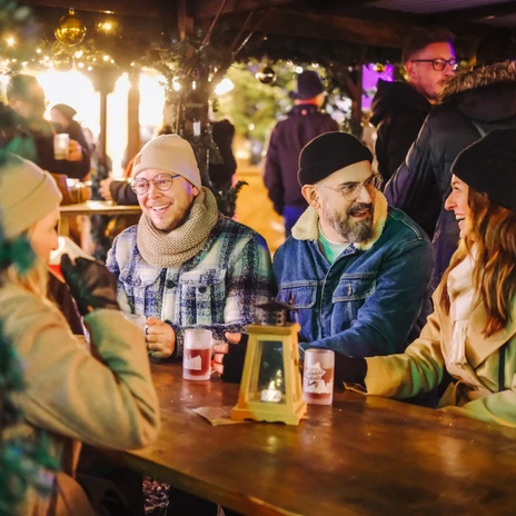 2401206_JS_159.JPG Eine Gruppe von Freunden sitzt an einem Holzstehtisch