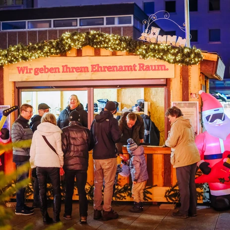 2401221_JS_021.JPG Menschen am Stand der Ehrenamtshütte auf dem Weihnachtsmarkt.