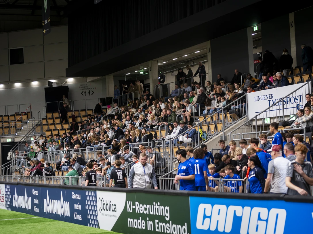 KampmannCup25_Foto_10.jpg Zuschauer verfolgen ein Hallenfußballturnier in der EmslandArena mit Spielern und Fans auf den Rängen.
