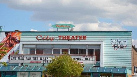 Außenansicht des Kinos Kultiplex City-Theater mit blauer Fassade, Programmtafel und Masken.