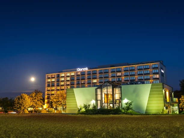 Dorint Hotel Main Taunus Zentrum - Außenansicht Hotelgebäude bei Nacht mit beleuchteter Fassade und Mond im Hintergrund
