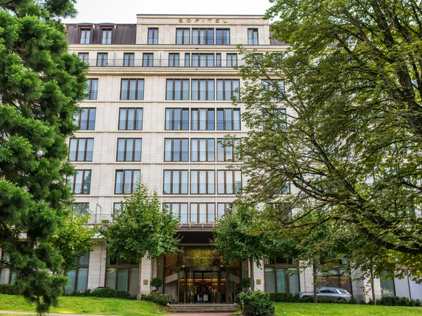 Sofitel Frankfurt Opera - Außenansicht Elegante Hotelfassade des Sofitel, umgeben von Bäumen und Grünflächen