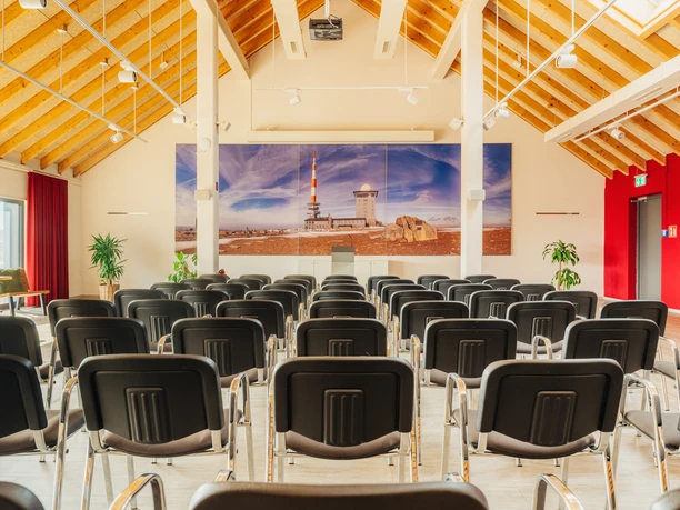 Torfhaus Harzresort - Tagungsraum mit Reihenbestuhlung Heller Tagungsraum mit Reihenbestuhlung im Torfhaus Harzresort. Die hohe Holzdecke, die große Fensterfront sowie das großes Harzpanorama an der Wand vermitteln Weite.