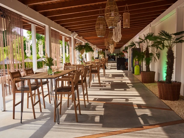 Chamäleon Location - Terrasse Holzterrasse der Chamäleon Location, dekoriert mit Palmen und möbliert für ein Event.
