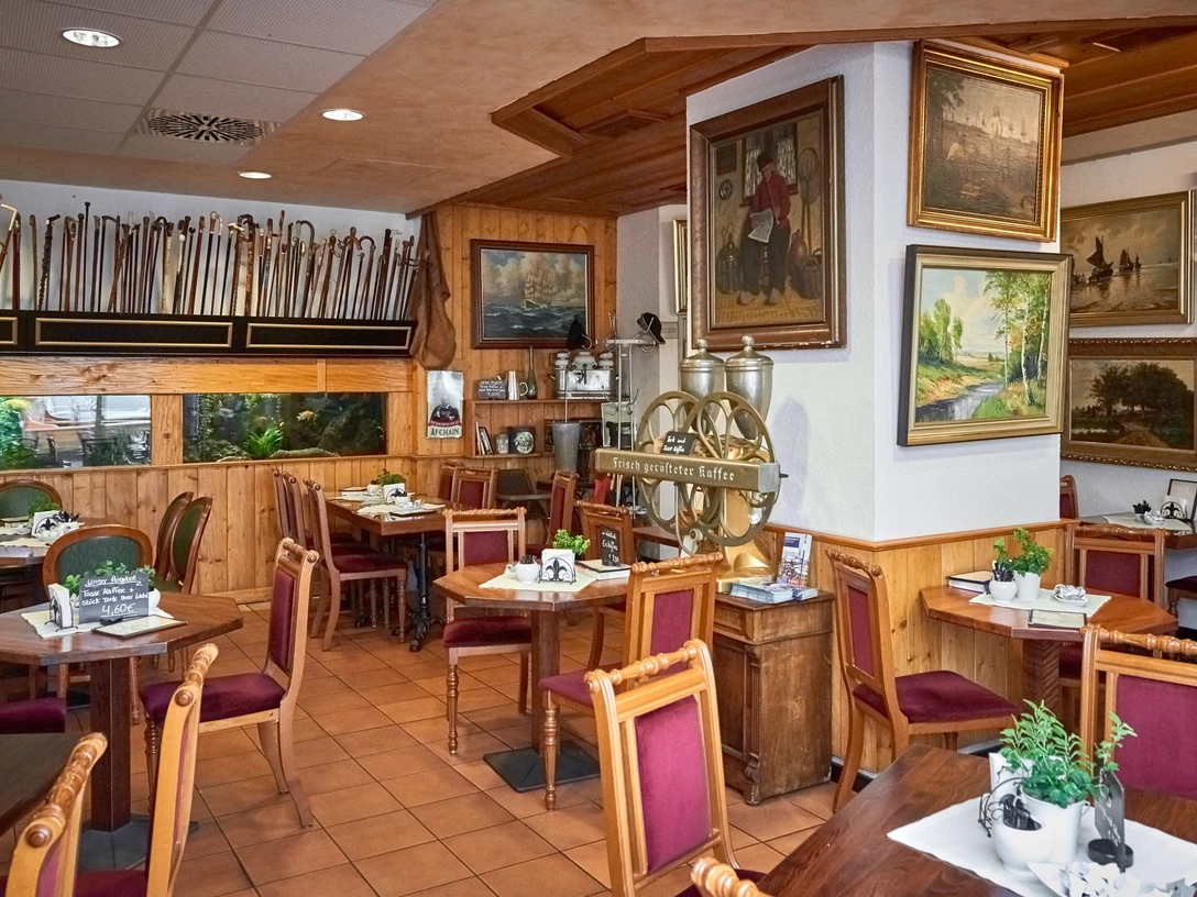 DSC_3858 (c) Anna Meurer_Erlebnis Bremerhaven.jpg Holzvertäfeltes Café mit maritimen Gemälden, alten Möbeln und großer Kaffeemaschine an der Wand.