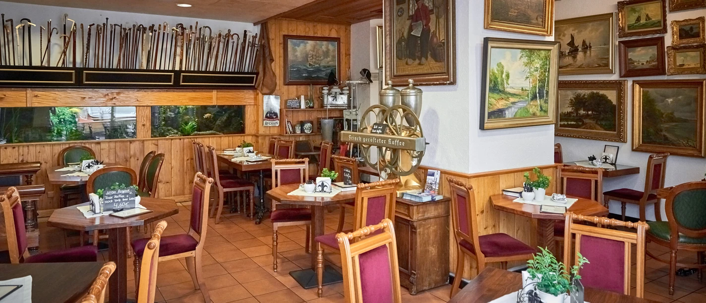 DSC_3858 (c) Anna Meurer_Erlebnis Bremerhaven.jpg Holzvertäfeltes Café mit maritimen Gemälden, alten Möbeln und großer Kaffeemaschine an der Wand.