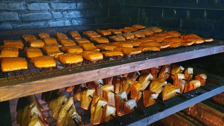 Frisch geräuchert bei Franke 20210422_103330 (c) Tanja Mehl_Erlebnis Bremerhaven GmbH.jpg Räucherofen mit goldbraunen Fischfilets auf Gittern und Holzstücken zum traditionellen Räuchern.