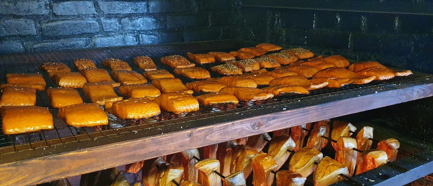Frisch geräuchert bei Franke 20210422_103330 (c) Tanja Mehl_Erlebnis Bremerhaven GmbH.jpg Räucherofen mit goldbraunen Fischfilets auf Gittern und Holzstücken zum traditionellen Räuchern.