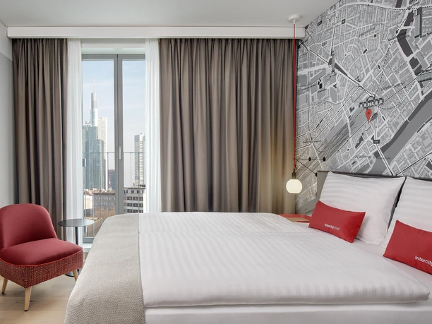 IntercityHotel Frankfurt Hauptbahnhof Süd - Hotel room interior view Single room with red armchair, large window and city map wallpaper.