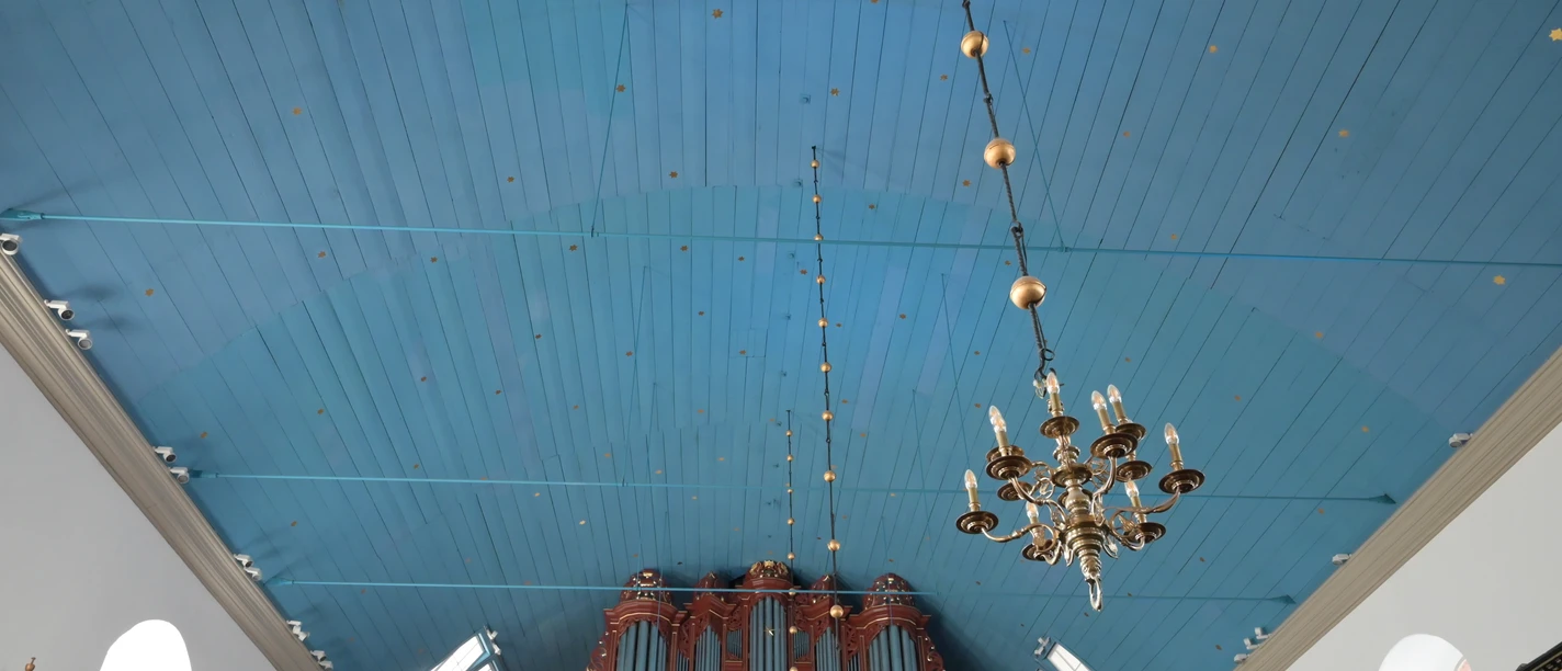 DSC_1944.JPG Blick auf die blaue Holzdecke einer Kirche mit kunstvoller Orgel und hängendem Kronleuchter.