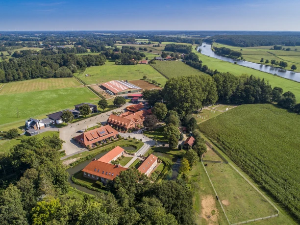 Luchtfoto van Landegge Estate met rode pannendaken, weiden, velden en rivier in Emsland.