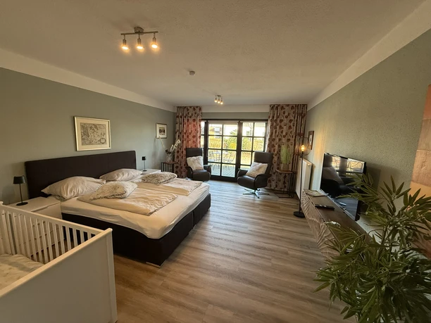 IMG_3390.JPEG Großes Familienzimmer mit Doppelbett, Kinderbett, Sitzbereich, Fernseher und Zugang zur Terrasse.