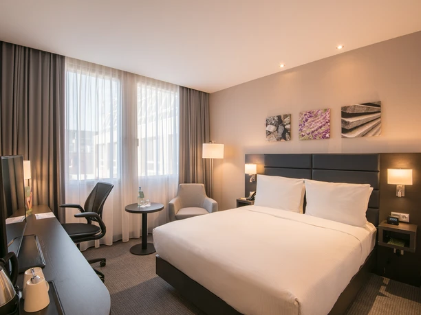 Hilton Garden Inn Frankfurt City - Hotelzimmer Modernes Hotelzimmer mit hellem Holz und Schreibtisch.
