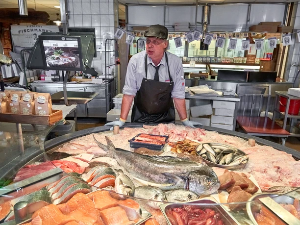 Fischverkauf DSC_3818 (c) Anna Meurer_Erlebnis Bremerhaven.jpg Fischhändler mit Schürze hinter einer Eistheke mit frischem Fisch und Meeresfrüchten in Bremerhaven