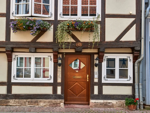 Fachwerkhäuser in Wolfenbüttel Fachwerkhausfassade mit braunen Balken, Holztür, weißen Fenstern und bunten Blumenkästen