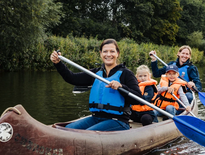 Familienzeit CR Kanu-Camp Lingen.jpg Familie paddelt lachend im Kanu auf der Ems, umgeben von grünem Ufer und ruhigem Wasser