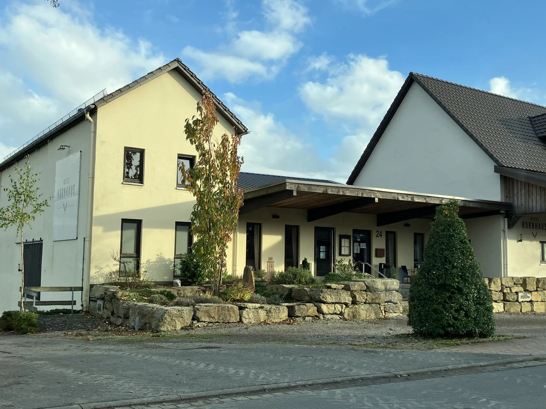 Restaurant Altes Kornhaus Helles Gebäude mit Schild „Altes Kornhaus“, Eingangsbereich und Steinmauer vor dem Eingang.