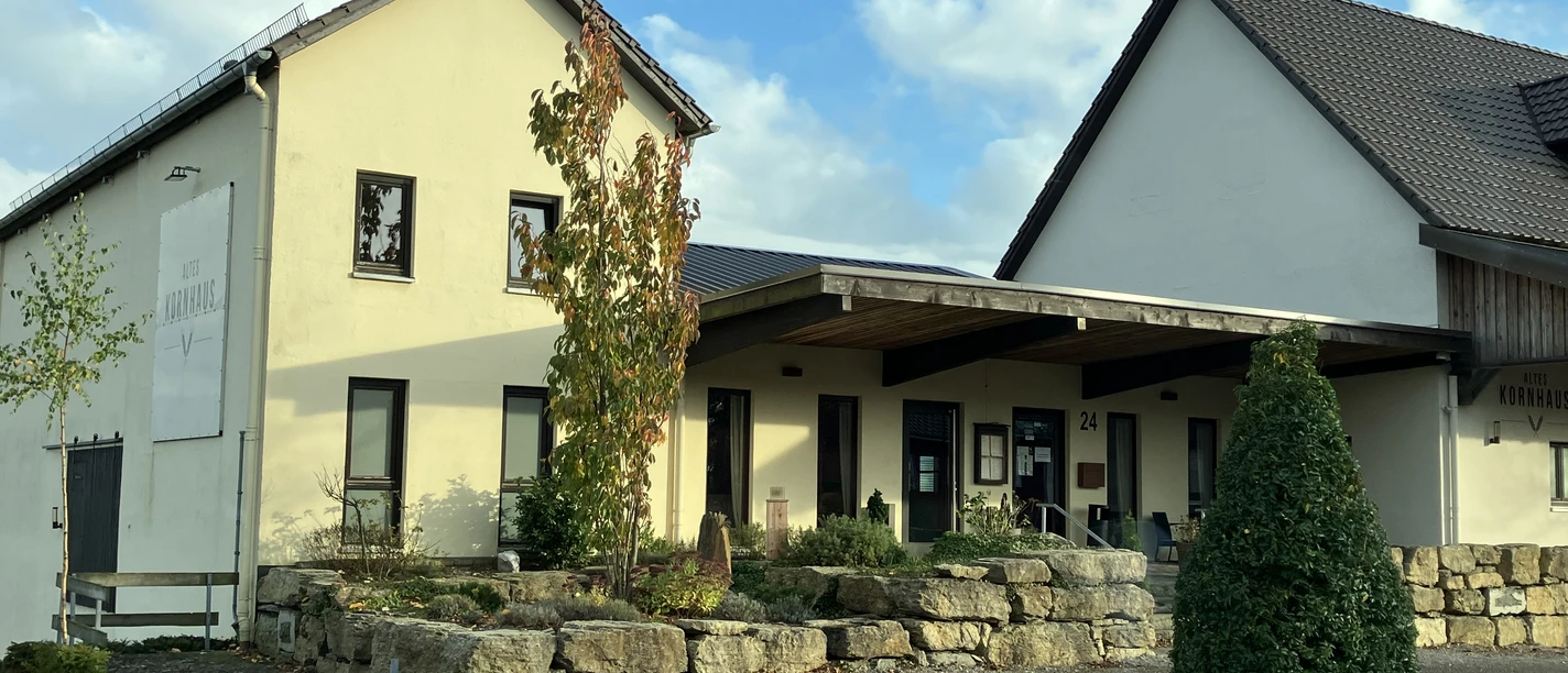 Restaurant Altes Kornhaus Helles Gebäude mit Schild „Altes Kornhaus“, Eingangsbereich und Steinmauer vor dem Eingang.