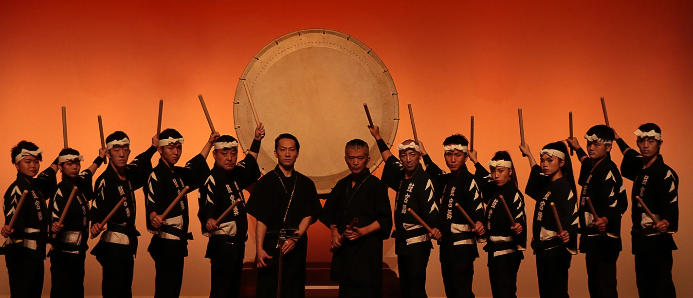 4. Pressebild 4 - Kokubu - 2026.jpg Gruppe japanischer Trommler in traditioneller Kleidung vor einer großen Taiko-Trommel auf Bühne