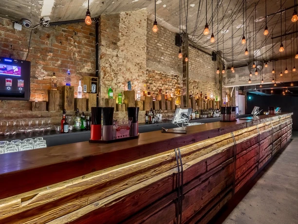 Gibson Club - Bar Moderner Bartresen mit einer Steinwand im Hintergrund und Lampen an der Decke