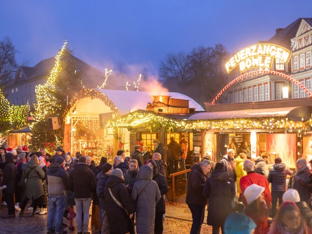 WF-Weihnachtsmarkt-Feuerzangenbowle 03.jpg Abendlicher Weihnachtsmarkt in Wolfenbüttel mit Lichterketten, Holzbuden und Besuchern bei Feuerzangenbowle