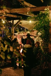 People in front of festively decorated stalls at night, surrounded by lights and decorations.