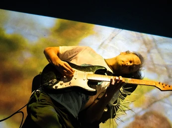 Cryptobiosis perfromance with electric guitar Ein Mensch liegt auf dem Boden und spielt dabei eine elektrische Gitarre.A person is lying on the floor playing an electric guitar.