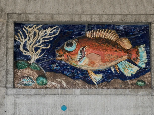 M3395 (c) Helmut Gross_Erlebnis Bremerhaven.jpg Keramikrelief eines roten Fisches mit Koralle und Muscheln auf blauem Grund an Betonwand.