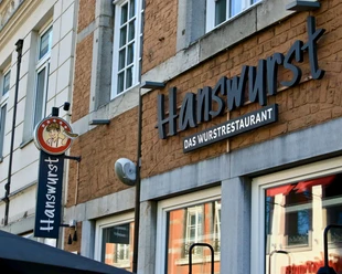Außenfassade des Restaurants "Hanswurst" mit Wandschild und großer Schrift des Namens.