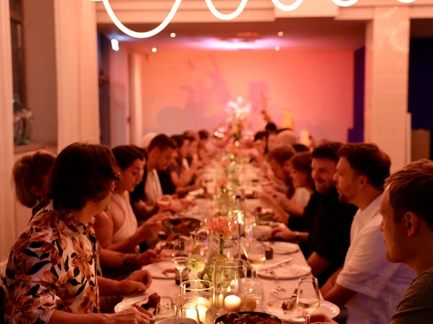 GOOSE Eventspace - Gesetztes Dinner Dinner an einer langen Tafel mit Menschen.