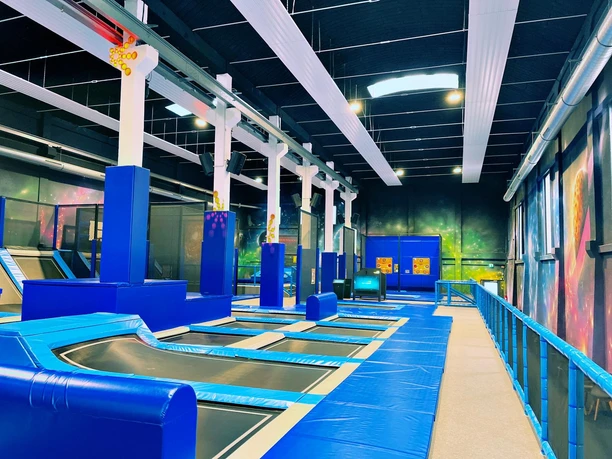 b4708411-c973-4ba9-ad02-5dd05f1a2b12 (c) Kai-Uwe Schulz_Erlebnis Bremerhaven.JPG Großer Indoor-Trampolinpark mit blauen Sprungflächen, Polstern und bunter Wandgestaltung.