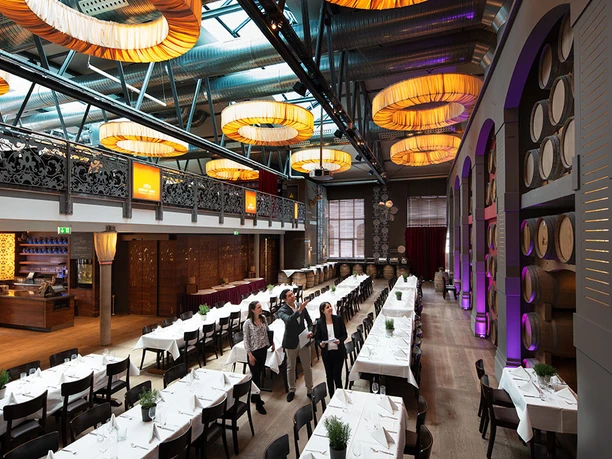Depot 1899 - Restaurantbereich Großer Saal mit gedeckten Tafeln und Holzfässern im Depot 1899