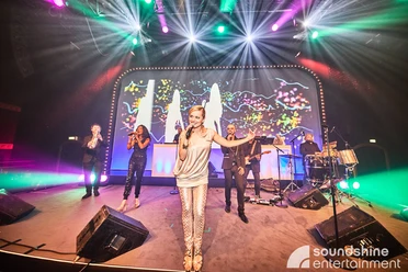 Soundshine Live Band.jpg Eine Band bestehend aus vier Sängerinnen und Sängern und einem Schlagzeuger steht auf der Bühne