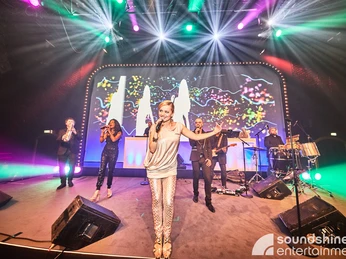 Soundshine Live Band.jpg Eine Band bestehend aus vier Sängerinnen und Sängern und einem Schlagzeuger steht auf der BühneA band consisting of four singers and a drummer takes to the stage