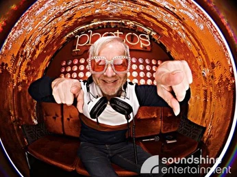 DJ.jpg DJ mit Glitzersonnenbrille und Kopfhörern um den Hals schaut in eine FischaugenkameraDJ with glitter sunglasses and headphones around his neck looks into a fisheye camera