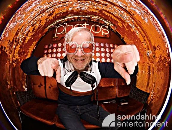 DJ.jpg DJ mit Glitzersonnenbrille und Kopfhörern um den Hals schaut in eine FischaugenkameraDJ with glitter sunglasses and headphones around his neck looks into a fisheye camera