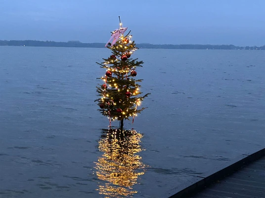 Weihnachtsbaum-im-Zwischenahner-Meer.jpg Beleuchteter Weihnachtsbaum steht im Zwischenahner Meer, Lichter spiegeln sich auf dem Wasser.