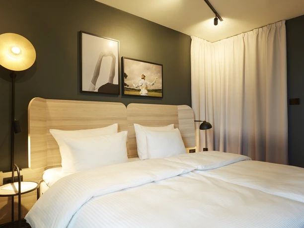 Scandic Frankfurt Hafenpark - Hotelzimmer Helles Hotelzimmer mit Doppelbett und stilvollen Wandbildern