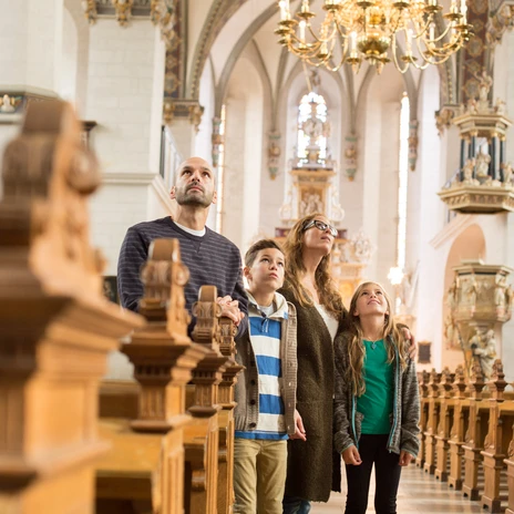 Eine Familie betrachtet im Kirchenraum von Wolfenbüttel aufmerksam die kunstvollen Verzierungen.