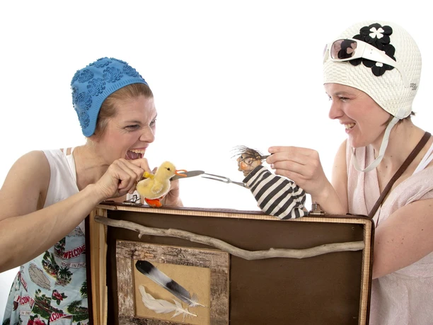 Kampf Figurentheater__MartinaBuchholz_WEB.jpg Zwei Frauen spielen mit Puppen eine humorvolle Theaterszene in einem kleinen Bühnenkoffer.
